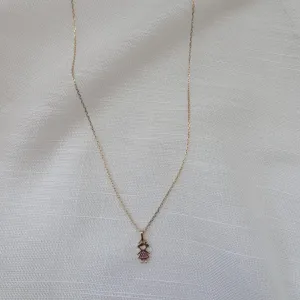 COLAR MENINA COM VESTIDO ROSA CRAVEJADO. 40CM DE COMPRIMENTO E 5CM DE REGULAGEM. BANHADO A OURO 18K.