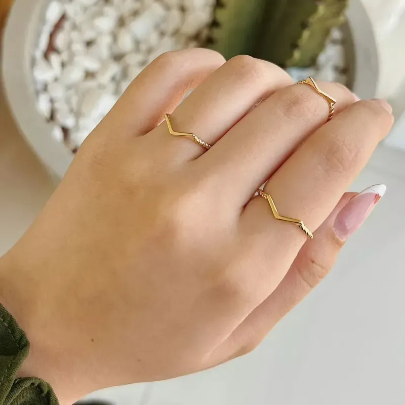 ANEL V COM MEIO ARO TORCIDO. BANHADO A OURO 18K.