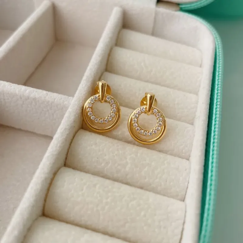 BRINCO 2 CÍRCULOS COM 1 CRAVEJADO. BANHADO A OURO 18K.