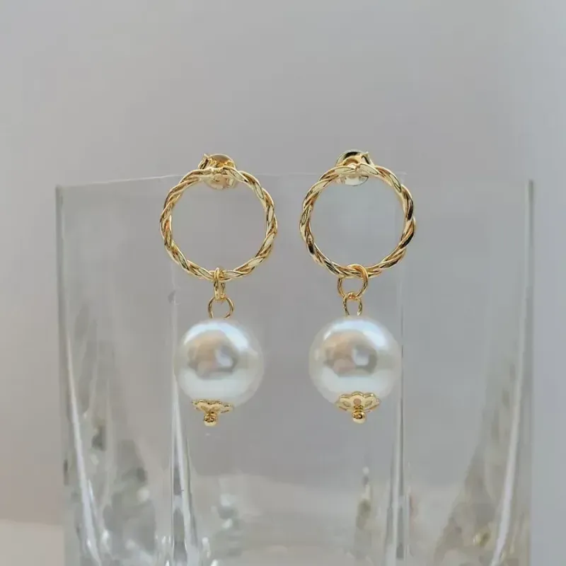 BRINCO CÍRCULO TORCIDO COM PÉROLA. BANHADO A OURO 18K.