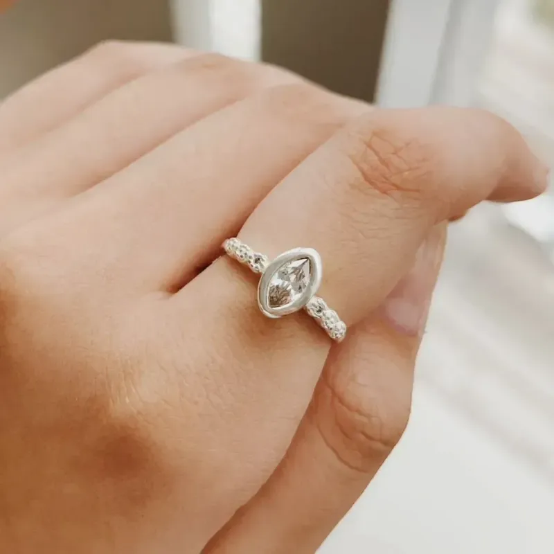 ANEL COM ZIRCÔNIA OVAL E ARO DETALHADO. EM PRATA 925.