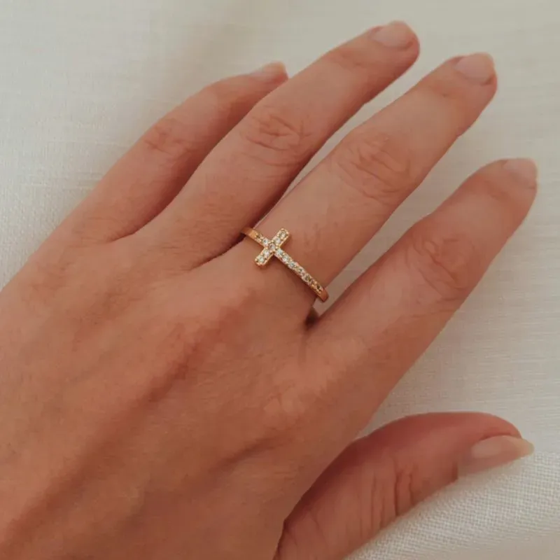 ANEL CRUZ HORIZONTAL CRAVEJADA. BANHADO A OURO 18K.