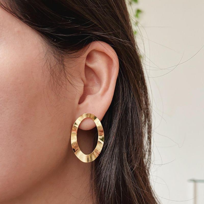 BRINCO ORGÂNICO OVAL VAZADO . BANHADO A OURO 18K.