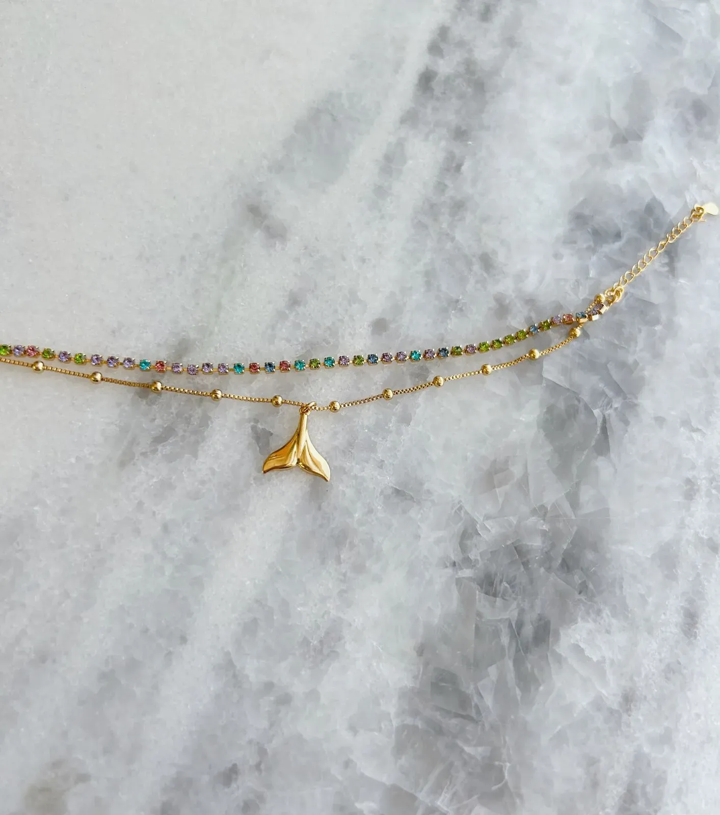 PULSEIRA DUPLA COM FIO DE ZIRCÔNIAS COLORIDAS E FIO DE BOLINHAS COM PINGENTE DE CAUDA DE SEREIA. 18 CM DE COMPRIMENTO E 3,5CM DE REGULAGEM.