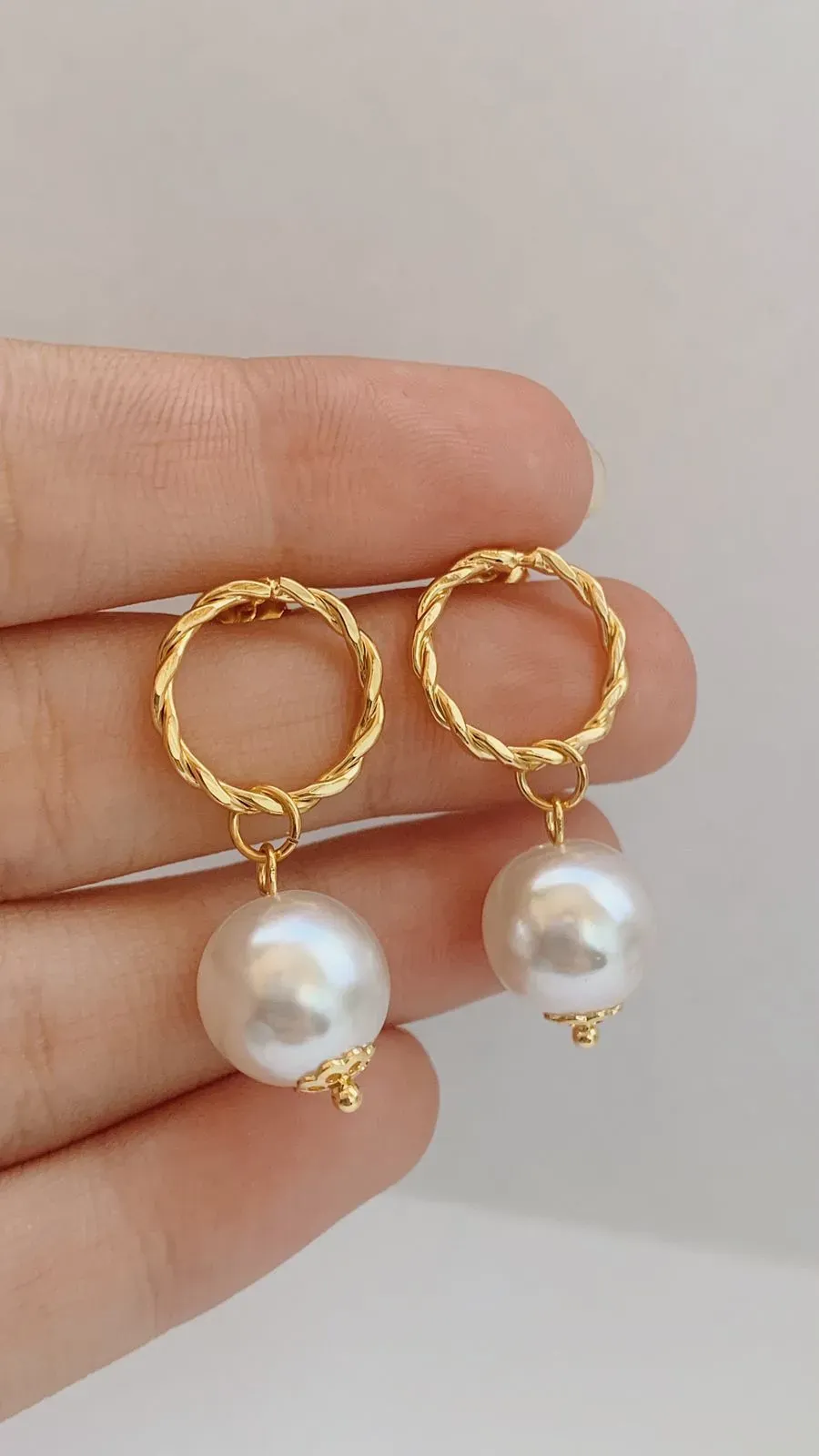 BRINCO CÍRCULO TORCIDO COM PÉROLA. BANHADO A OURO 18K.