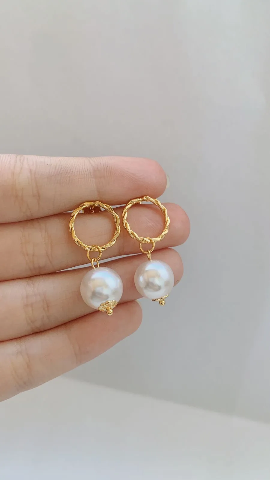 BRINCO CÍRCULO TORCIDO COM PÉROLA. BANHADO A OURO 18K.