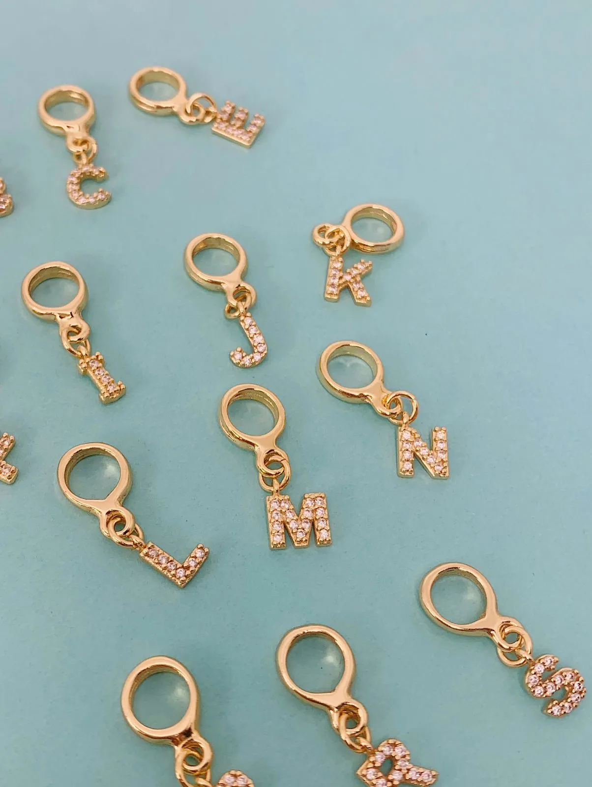 BERLOQUE DE LETRA M CRAVEJADO. BANHADO A OURO 18K.