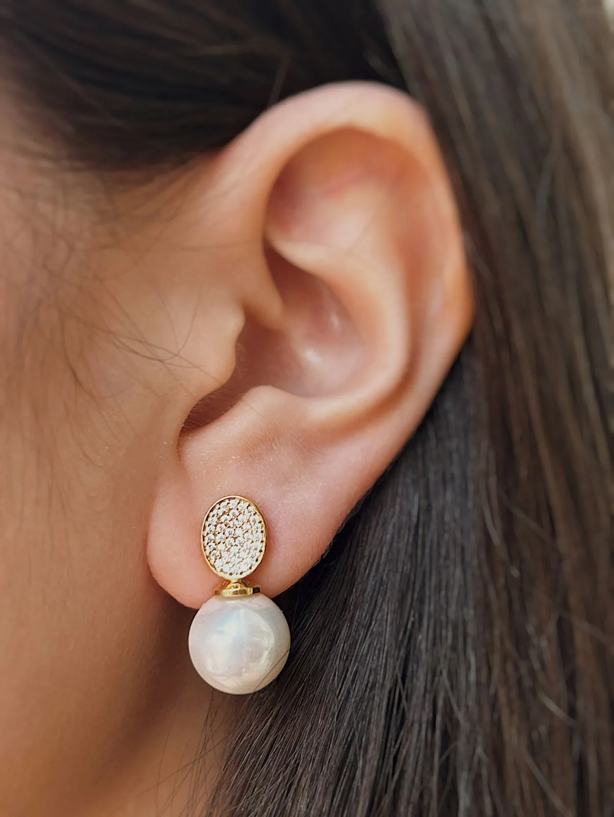 BRINCO COM DETALHE OVAL CRAVEJADO E PÉROLA. BANHADO A OURO 18K.