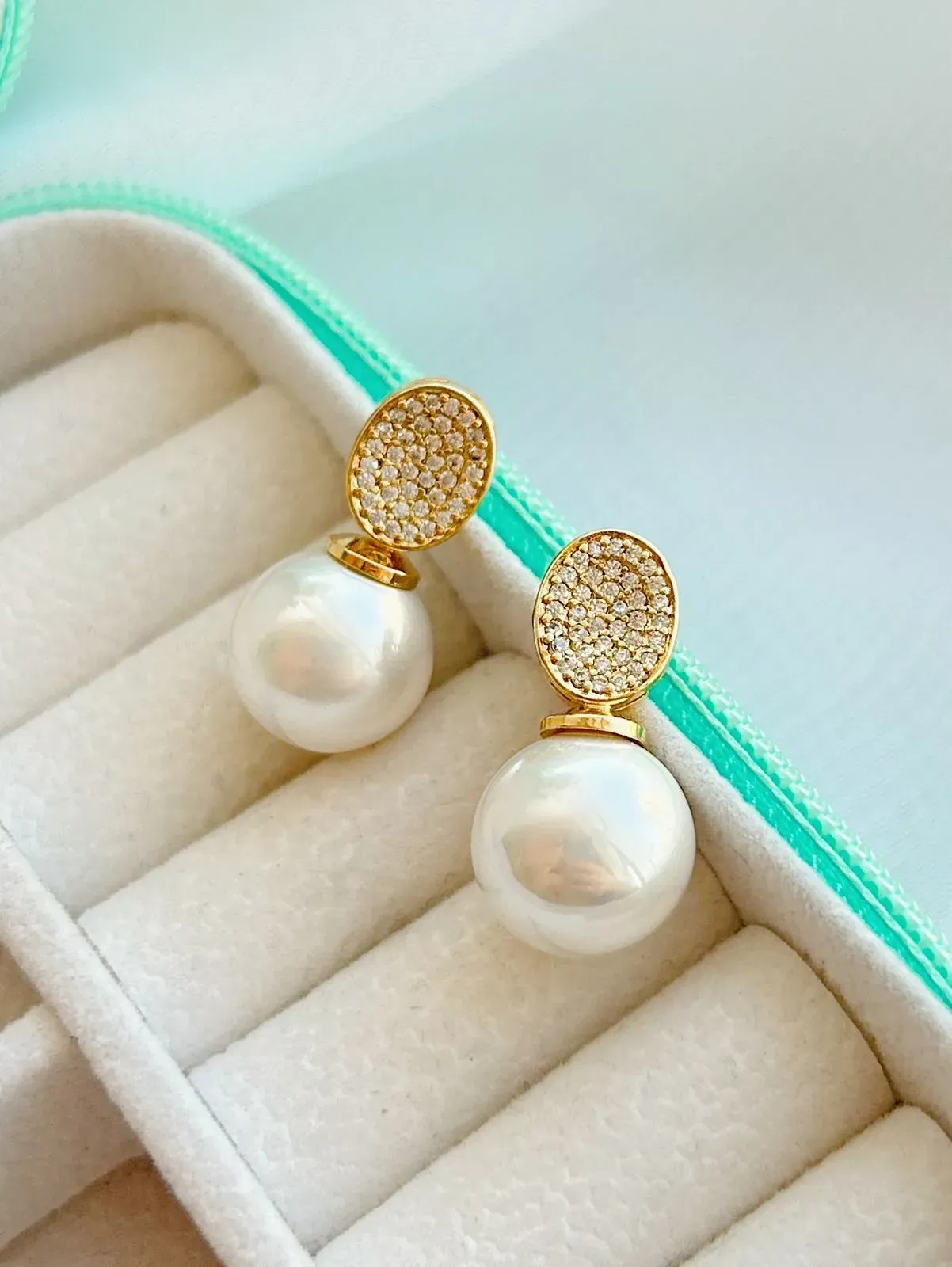 BRINCO COM DETALHE OVAL CRAVEJADO E PÉROLA. BANHADO A OURO 18K.