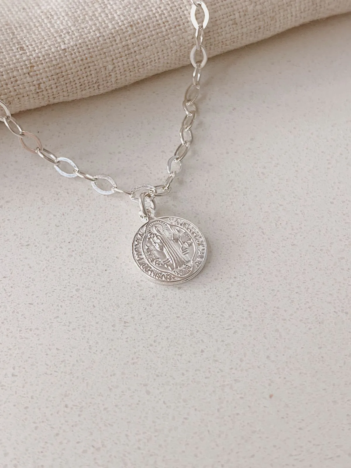 PULSEIRA ELOS COM PINGENTE DE MEDALHA DE SÃO BENTO COM 1CM DE DIÂMETRO. 17,5CM DE COMPRIMENTO E 1CM DE REGULAGEM. EM PRATA 925.