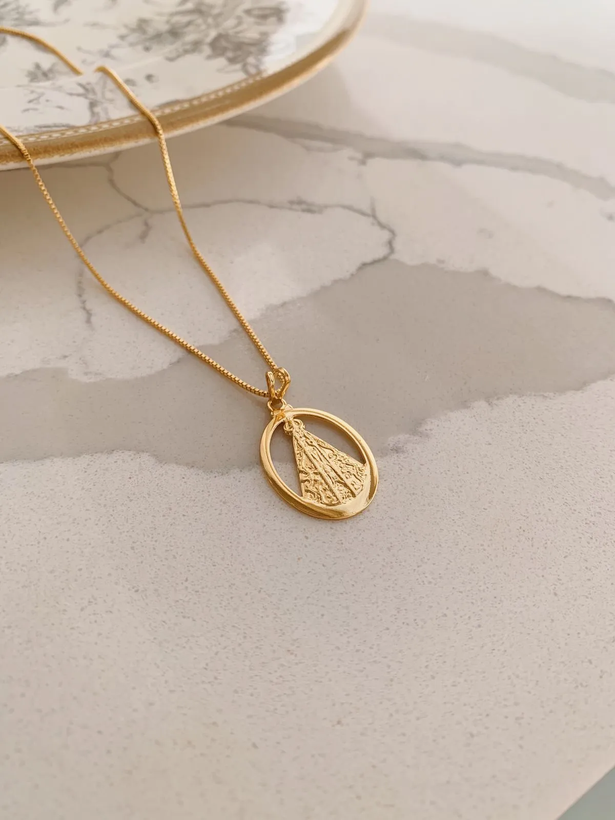 COLAR NOSSA SENHORA COM MEDALHA OVAL VAZADA. 45CM DE COMPRIMENTO E 5CM DE REGULAGEM. BANHADO A OURO 18K.