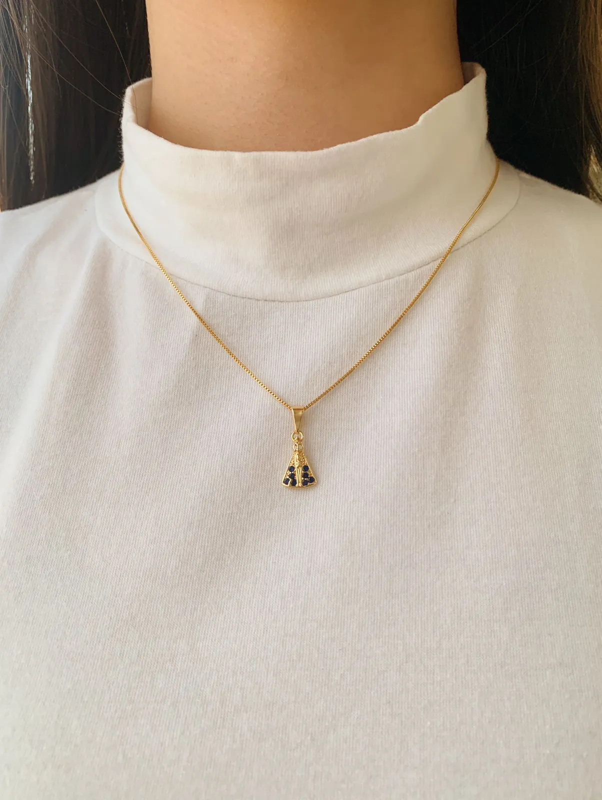 COLAR COM PINGENTE DE NOSSA SENHORA CRAVEJADA EM AZUL. 45CM DE COMPRIMENTO E 5CM DE REGULAGEM. BANHADO A OURO 18K.