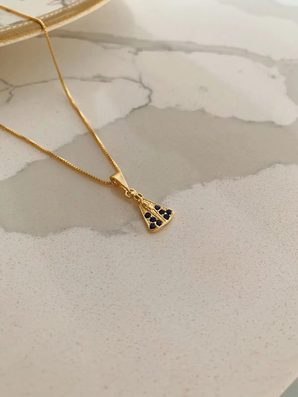 COLAR COM PINGENTE DE NOSSA SENHORA CRAVEJADA EM AZUL. 45CM DE COMPRIMENTO E 5CM DE REGULAGEM. BANHADO A OURO 18K.