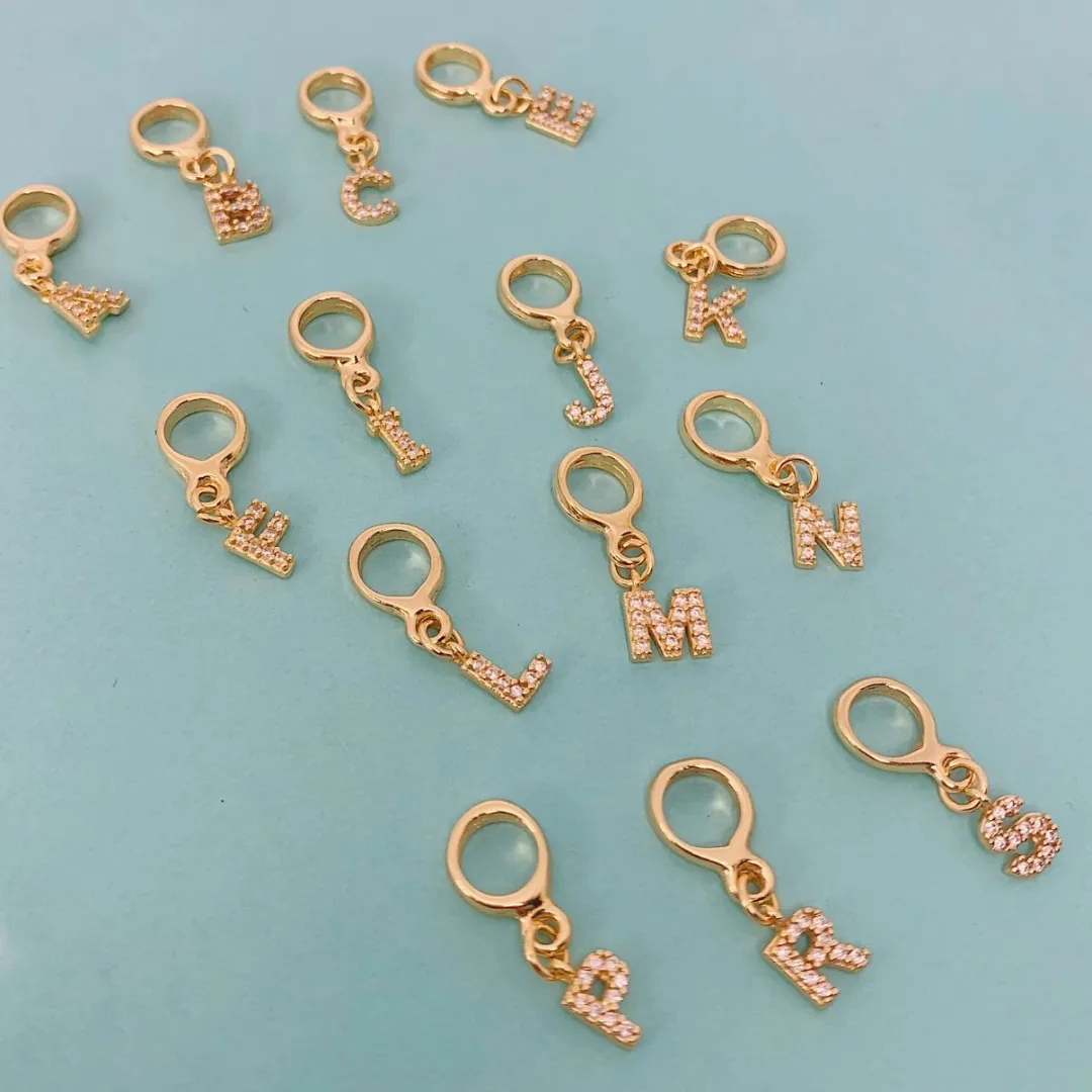 BERLOQUE DE LETRA G CRAVEJADO. BANHADO A OURO 18K.