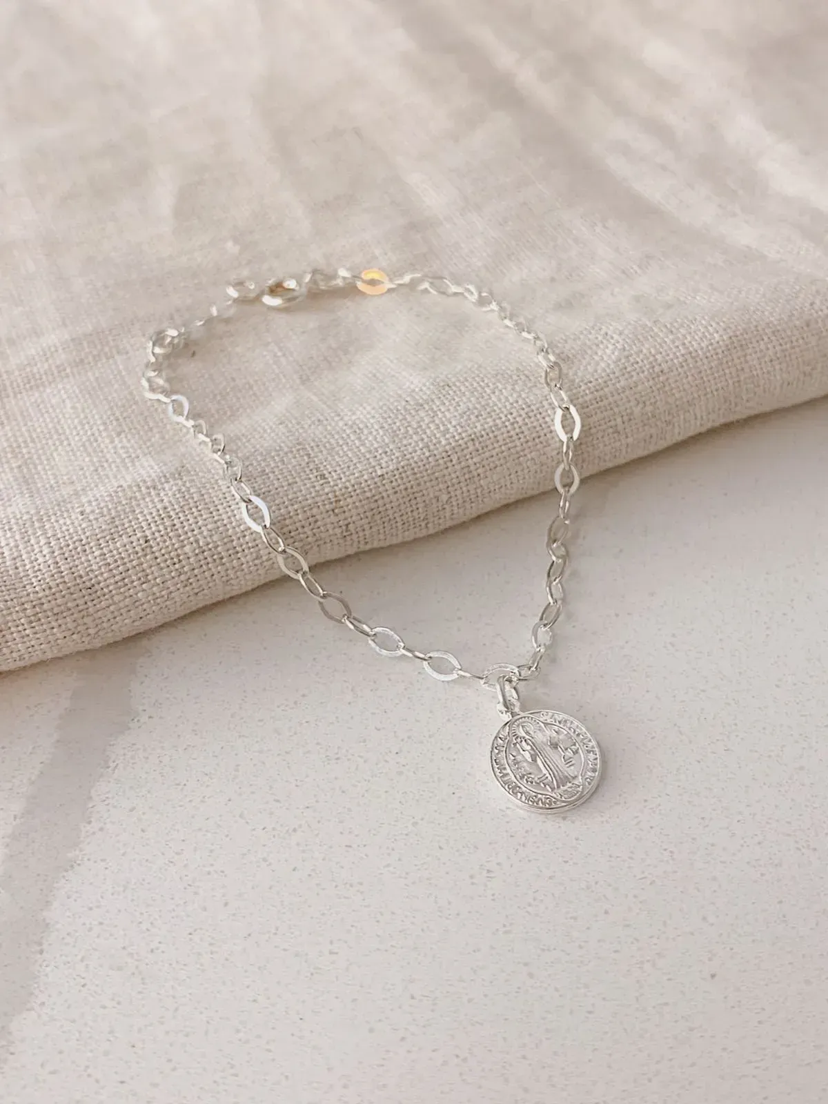 PULSEIRA ELOS COM PINGENTE DE MEDALHA DE SÃO BENTO COM 1CM DE DIÂMETRO. 17,5CM DE COMPRIMENTO E 1CM DE REGULAGEM. EM PRATA 925.