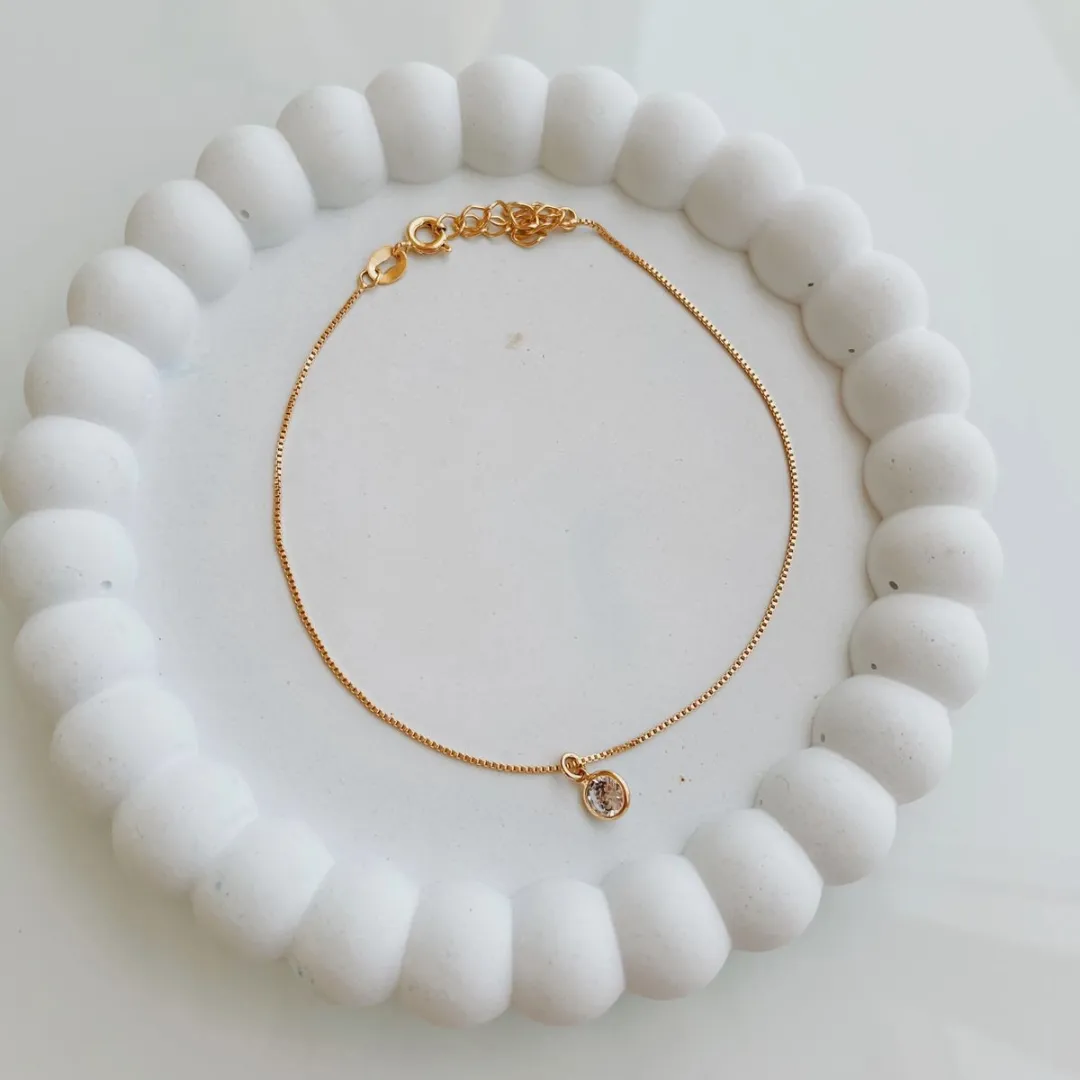 TORNOZELEIRA COM PONTO DE LUZ. 22CM DE COMPRIMENTO E 5CM DE REGULAGEM. BANHADA A OURO 18K.