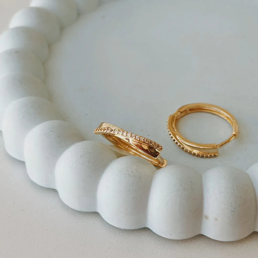 BRINCO ARGOLA COM FIO CRUZADO CRAVEJADO. FECHO CLICK. BANHADO A OURO 18K.