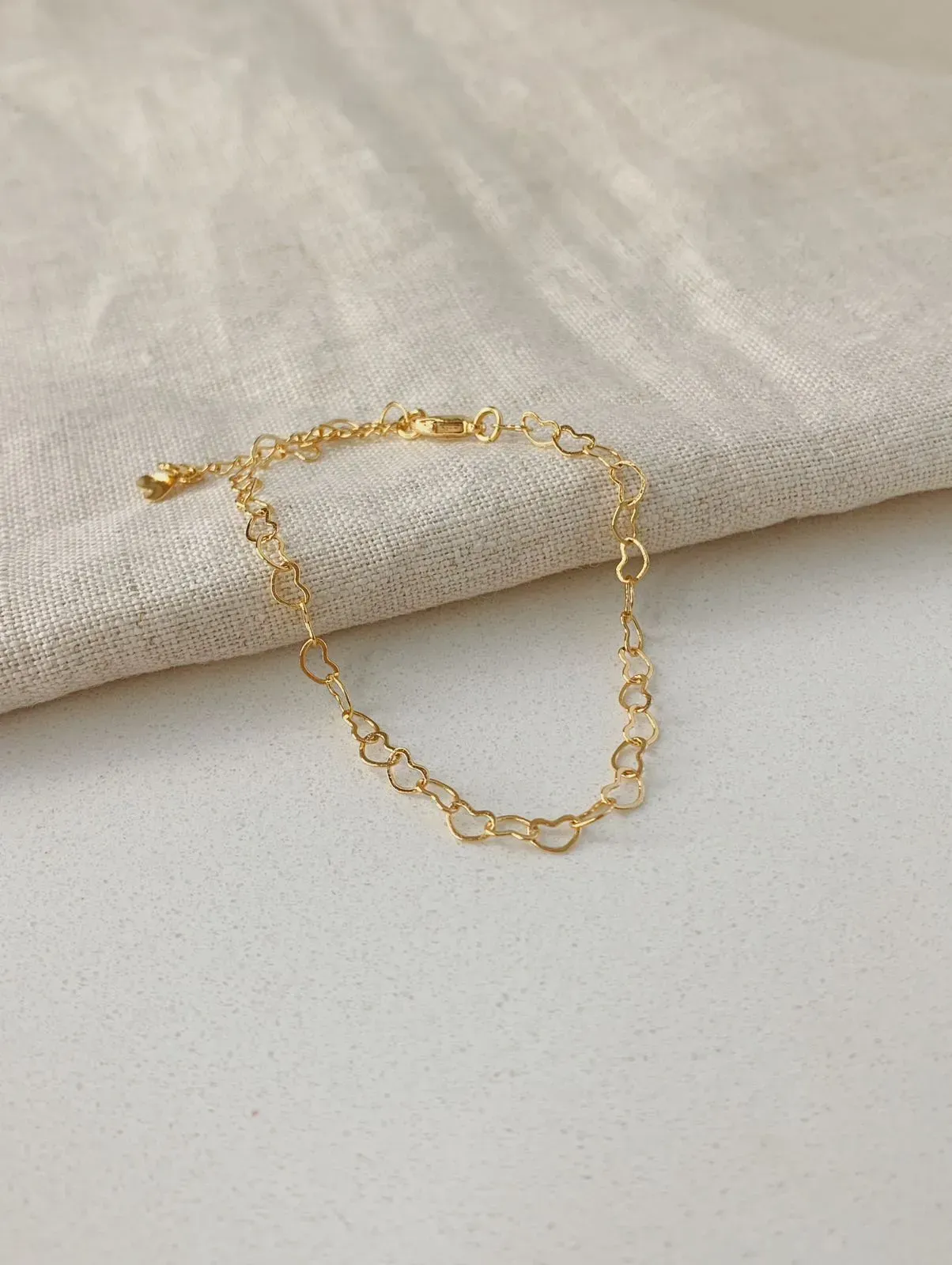 PULSEIRA COM ELOS DE CORAÇÃO. 17CM DE COMPRIMENTO E 3CM DE REGULAGEM. BANHADA A OURO 18K.