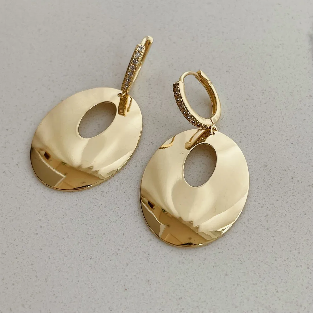 BRINCO ARGOLA CRAVEJADA COM PINGENTE CIRCULO VAZADO BANHADO A OURO 18K.