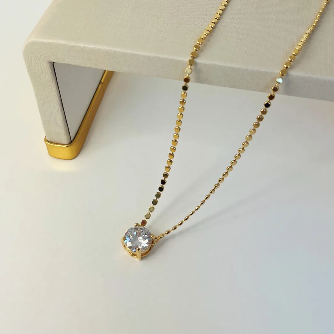 COLAR BOLINHAS ACHATADAS COM PONTO DE LUZ 10MM. 45CM DE COMPRIMENTO E 5CM DE REGULAGEM. BANHADO A OURO 18K.