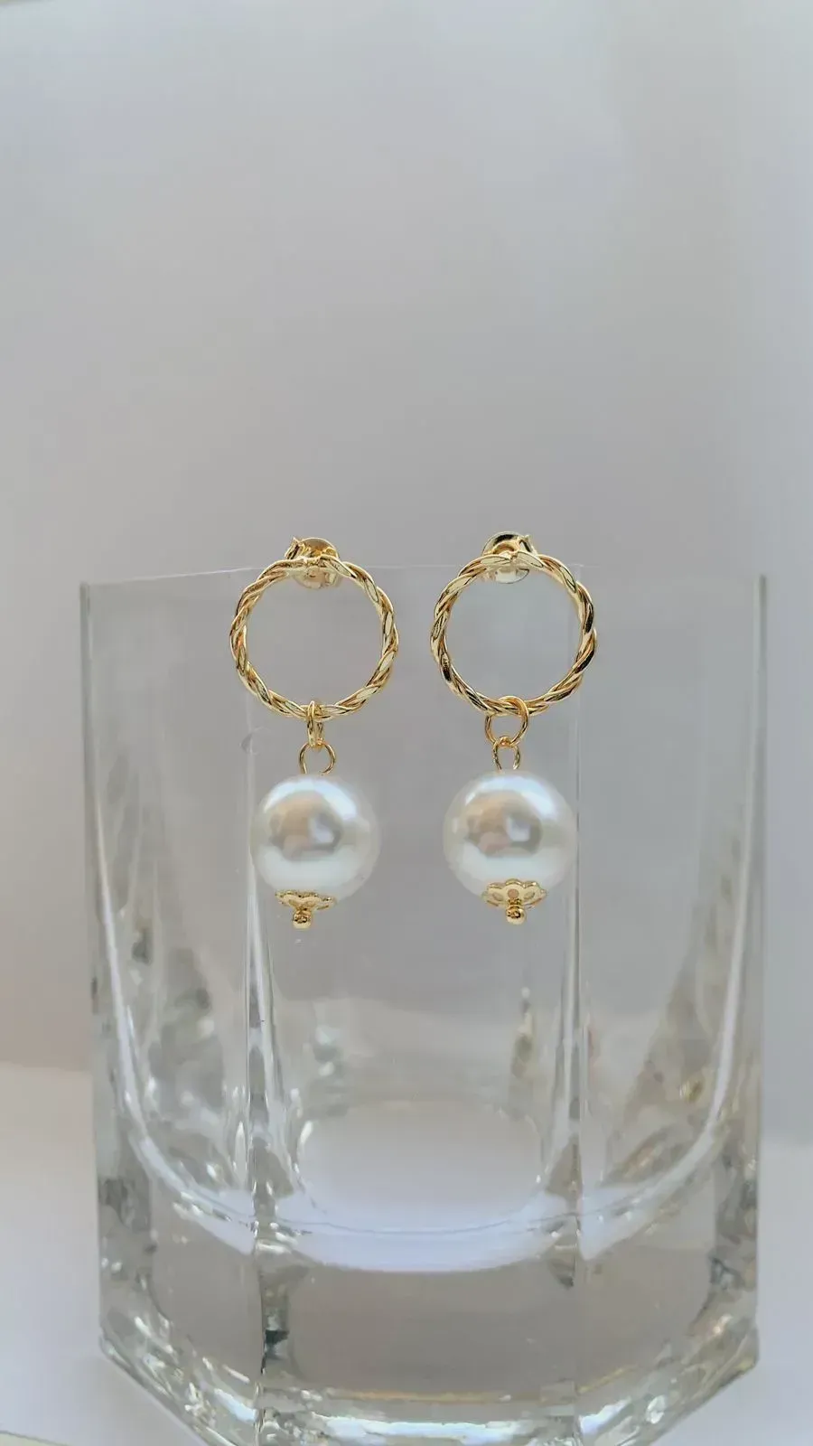 BRINCO CÍRCULO TORCIDO COM PÉROLA. BANHADO A OURO 18K.