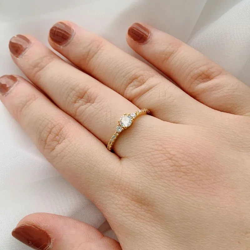 ANEL SOLITÁRIO COM 2 ZIRCÔNIAS E ARO CRAVEJADO. BANHADO A OURO 18K.